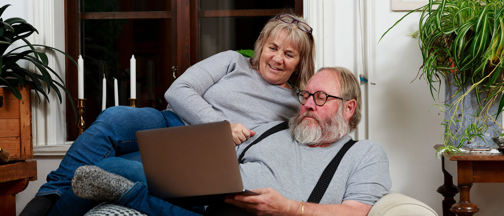 Ett äldre par sitter i soffan och tittar på en laptop tillsammans